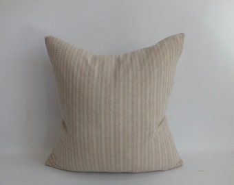 May include: A beige striped pillow with a subtle texture. The pillow is made of a soft, natural fabric and has a simple, elegant design.