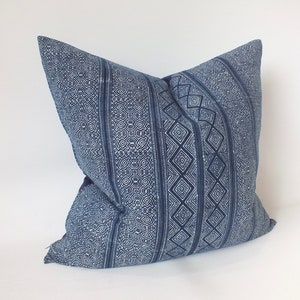 May include: A blue and white patterned cushion with a geometric design. The cushion is made of a soft, woven fabric.