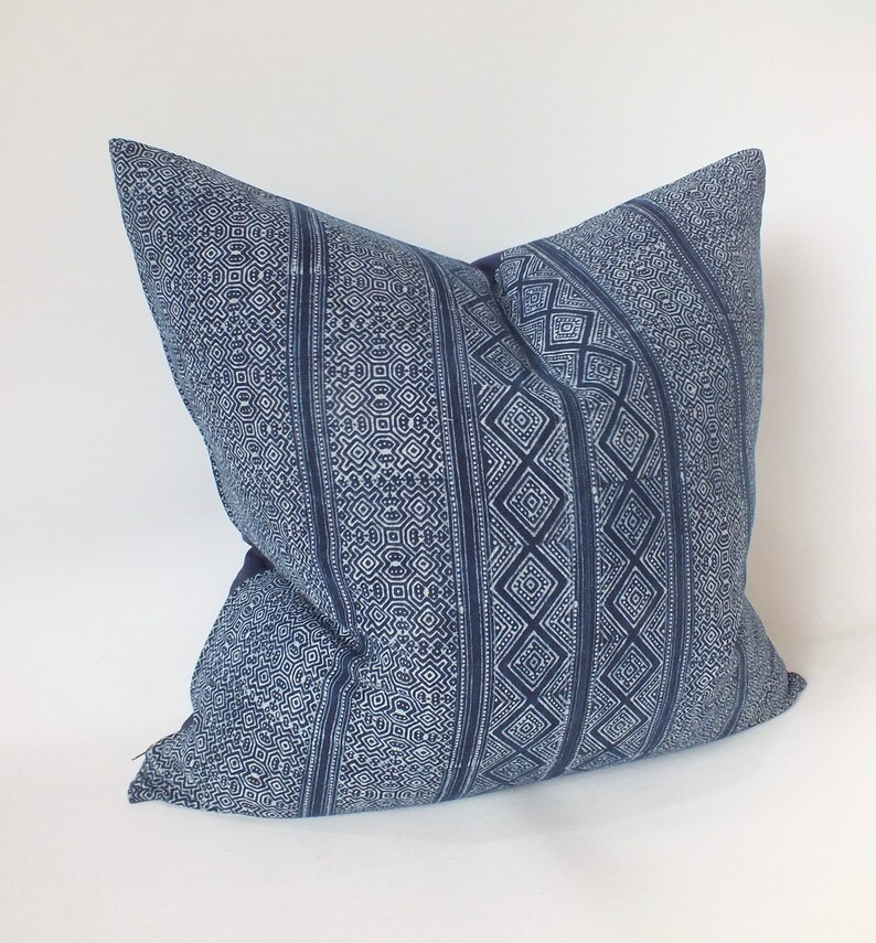 May include: A blue and white patterned cushion with a geometric design. The cushion is made of a soft, woven fabric.