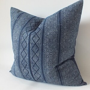 May include: A blue and white patterned cushion with a geometric design. The cushion is made of a soft, woven fabric.