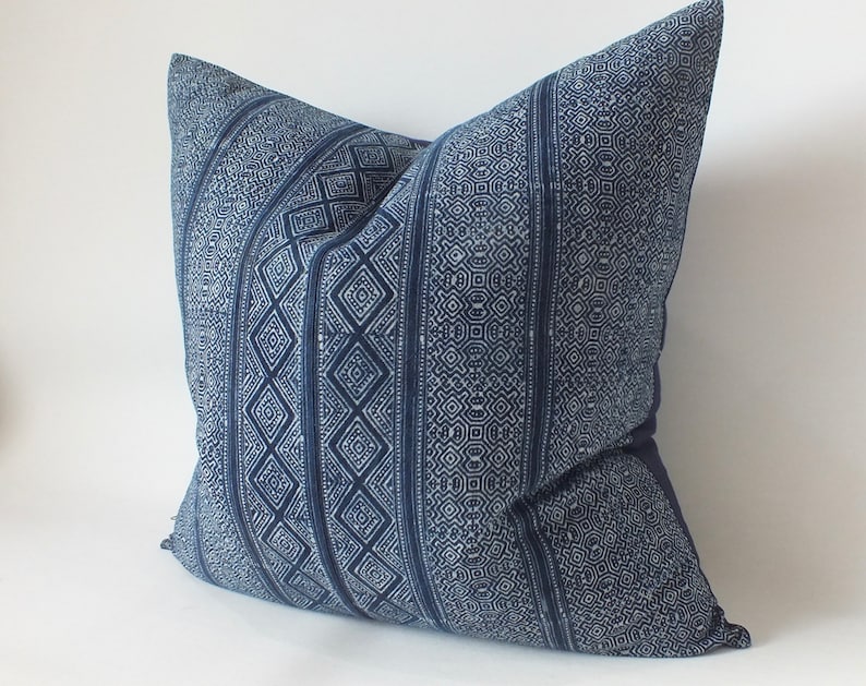 May include: A blue and white patterned cushion with a geometric design. The cushion is made of a soft, woven fabric.
