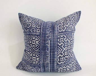 May include: Square throw pillow with a blue and white geometric pattern. The pillow features a central vertical band with a repeating design, and the overall pattern includes diamonds and other shapes.