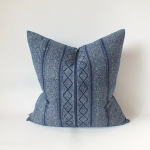 May include: A blue and white patterned cushion with a geometric design. The cushion is made of a soft, woven fabric.