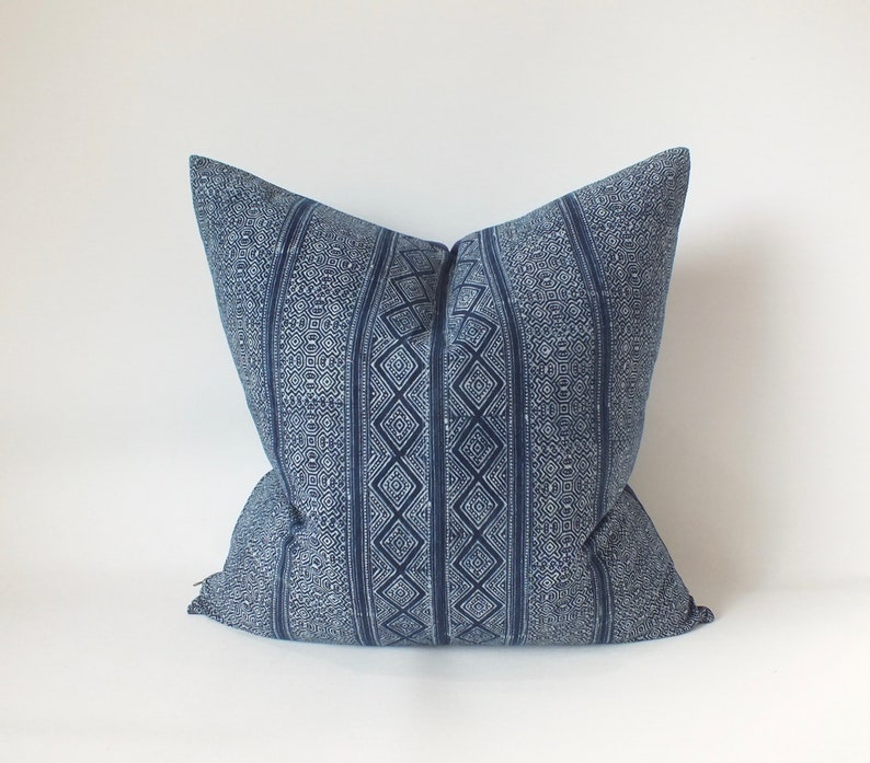 May include: A blue and white patterned cushion with a geometric design. The cushion is made of a soft, woven fabric.