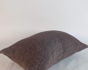 May include: A rectangular throw pillow featuring a dark brown fabric with a visible, textured weave pattern. The pillow has a slightly rounded, plump shape and is presented against a plain, neutral background, highlighting the woven material.