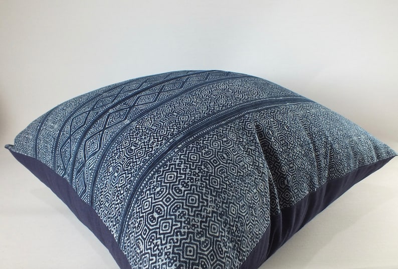 May include: A blue and white patterned cushion with a geometric design. The cushion is made of a soft, woven fabric and has a dark blue border.