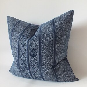 May include: A blue and white patterned cushion with a geometric design. The cushion is made of a soft, woven fabric.