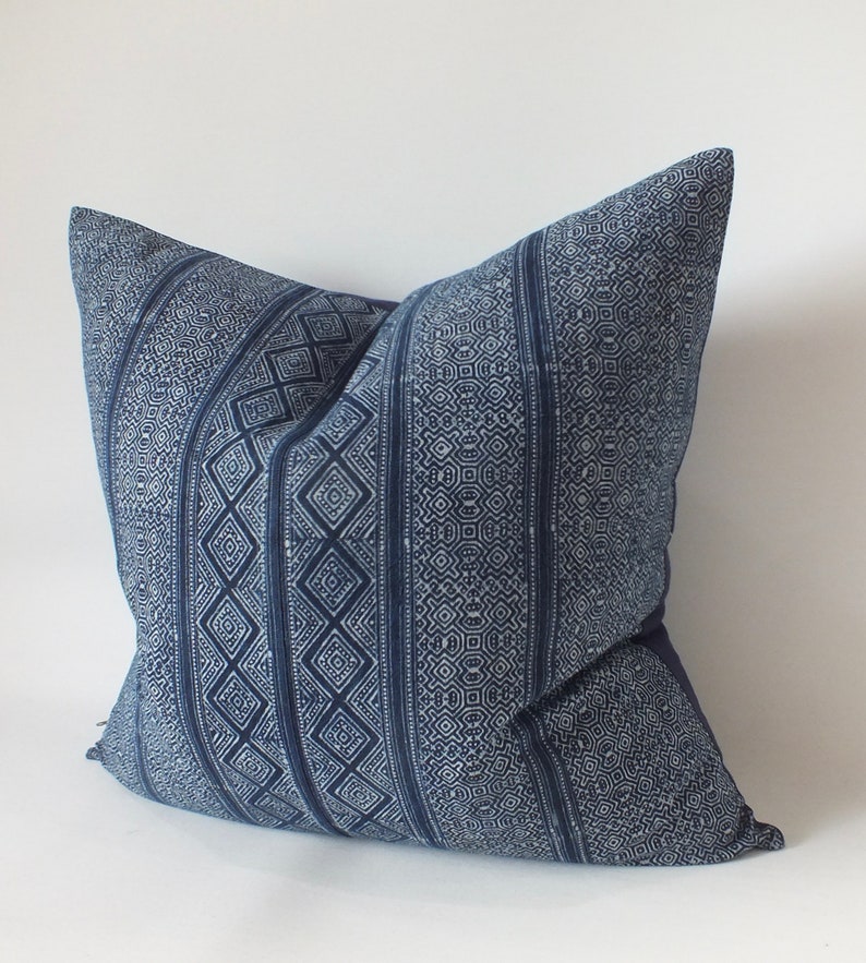May include: A blue and white patterned cushion with a geometric design. The cushion is made of a soft, woven fabric.
