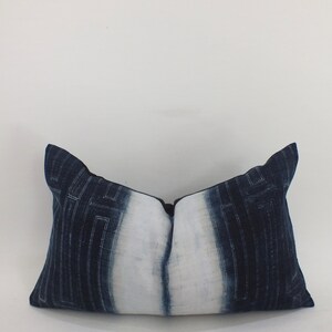 May include: A long, rectangular pillow with a white center and dark blue edges. The pillow has a geometric pattern in a lighter shade of blue.
