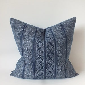 May include: A blue and white patterned cushion with a geometric design. The cushion is made of a soft, woven fabric.