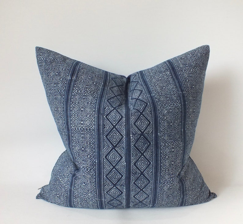 May include: A blue and white patterned cushion with a geometric design. The cushion is made of a soft, woven fabric.