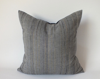 May include: A gray and black striped throw pillow with a black border. The pillow is made of a soft, textured fabric.