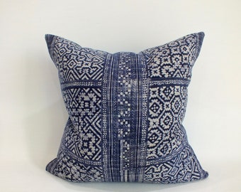 May include: Square decorative pillow with a navy blue and white geometric pattern. The pillow features a central vertical stripe and a repeating diamond and square design. The fabric has a textured appearance.