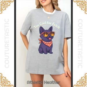 Może przedstawiać: Szara koszulka z nadrukiem fioletowego psa w okularach przeciwsłonecznych i czerwonej chuście. Nadruk zawiera napis "Too Cool for Fetch". Koszulka ma biały kołnierzyk.