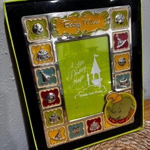 May include: A decorative photo frame with a black frame and a lime green border. The frame has a green interior and is decorated with colorful squares and a Dumbo the Elephant graphic. The text "Baby Mine" is displayed at the top.