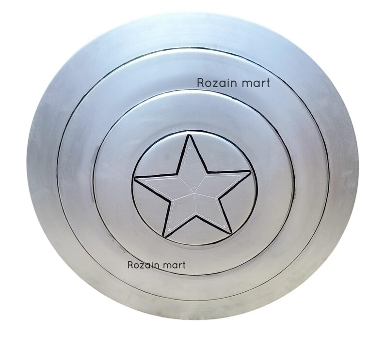 May include: A silver-colored, circular shield with concentric rings and a central five-pointed star. The shield has a metallic sheen and a raised star design. The text "Rozain mart" is printed on the shield.