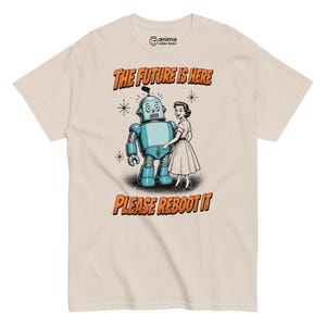 Puede incluir: Una camiseta beige con un gráfico de estilo retro de un robot azul y una persona. El texto dice THE FUTURE IS HERE y PLEASE REBOOT IT en letras naranjas. El diseño incluye pequeños detalles de estrellas y el logo anima della festa arriba.