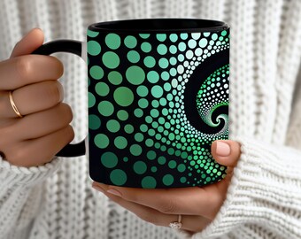 May include: Black coffee mug with a green and white spiral dot design. The mug has a black handle and rim. The design features a gradient of green dots, creating a spiral pattern against a black background. The mug is held by a person wearing a white sweater.