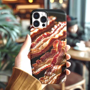 Könnte beinhalten: Eine Handyhülle mit einem Nahaufnahmebild von gebratenem Speck. Die Speckstreifen sind eine Mischung aus Rot und Braun mit knusprigen Rändern. Die Hülle hat einen schwarzen Rand und einen Ausschnitt für die Kameralinse.