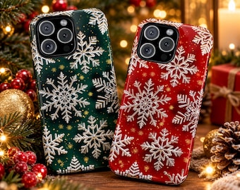 Puede incluir: Dos fundas para smartphone, una en verde oscuro y otra en rojo vibrante, ambas con un patrón de copos de nieve plateados en relieve y pequeños detalles de purpurina dorada. Cada funda tiene una abertura para la cámara.