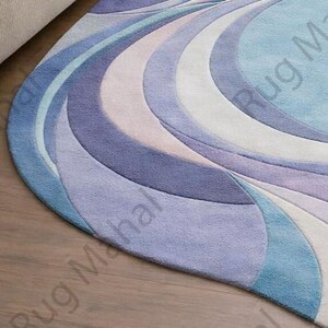 Abstract swirl shaped pastel area rug in blue, purple and white colors styled in a modern living room interior