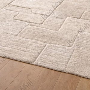 Ivory textured geometric area rug styled in a modern minimalist living room with neutral furniture.