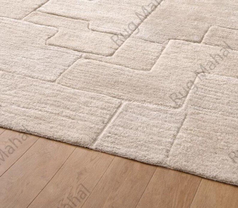 Ivory textured geometric area rug styled in a modern minimalist living room with neutral furniture.