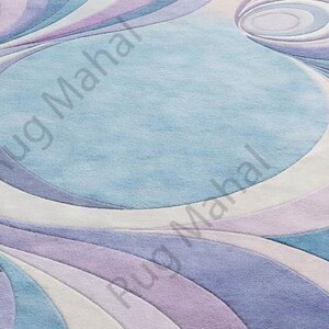 Abstract swirl shaped pastel area rug in blue, purple and white colors styled in a modern living room interior