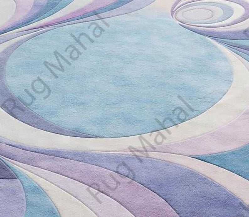 Abstract swirl shaped pastel area rug in blue, purple and white colors styled in a modern living room interior