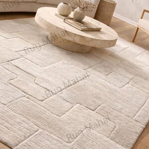 Ivory textured geometric area rug styled in a modern minimalist living room with neutral furniture.