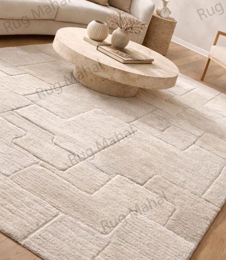 Ivory textured geometric area rug styled in a modern minimalist living room with neutral furniture.