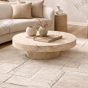 Ivory textured geometric area rug styled in a modern minimalist living room with neutral furniture.