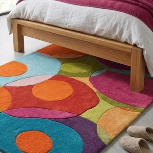 Colorful rug partially placed under a bed adding warmth and personality.