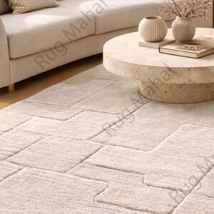 Ivory textured geometric area rug styled in a modern minimalist living room with neutral furniture.