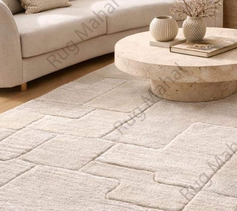 Ivory textured geometric area rug styled in a modern minimalist living room with neutral furniture.