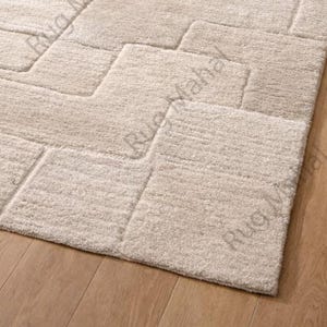 Ivory textured geometric area rug styled in a modern minimalist living room with neutral furniture.