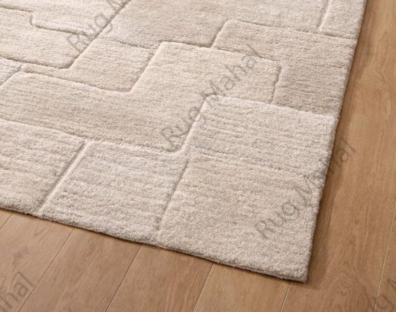Ivory textured geometric area rug styled in a modern minimalist living room with neutral furniture.