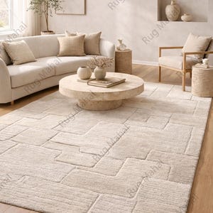 Ivory textured geometric area rug styled in a modern minimalist living room with neutral furniture.