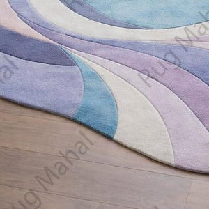 Abstract swirl shaped pastel area rug in blue, purple and white colors styled in a modern living room interior