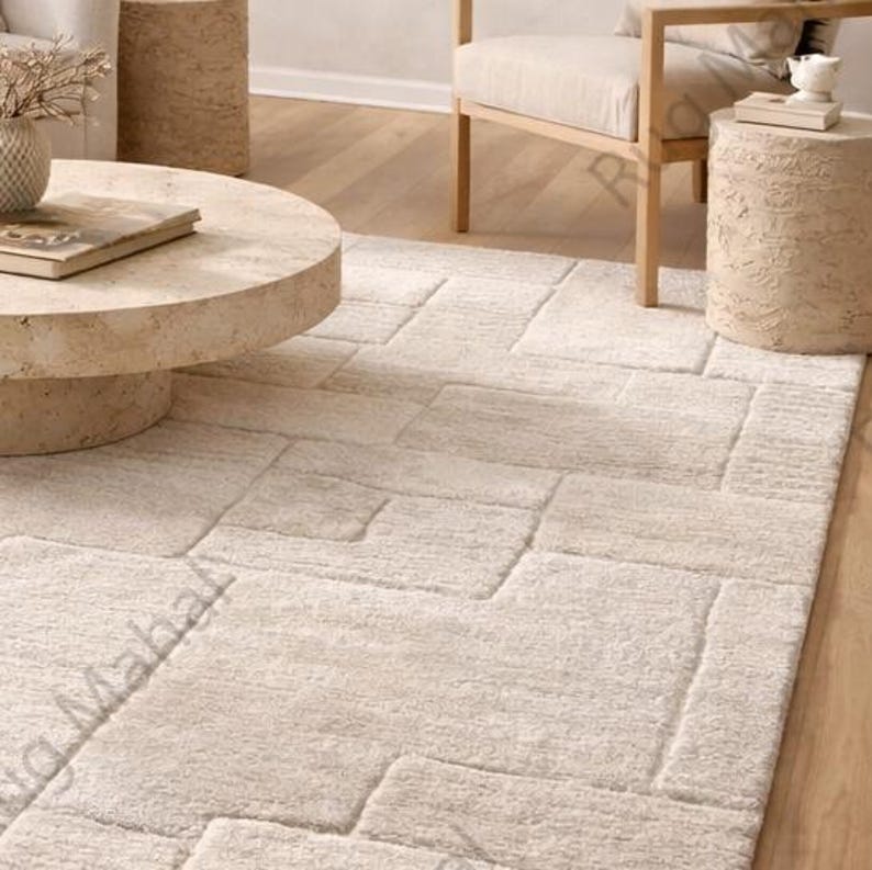 Ivory textured geometric area rug styled in a modern minimalist living room with neutral furniture.