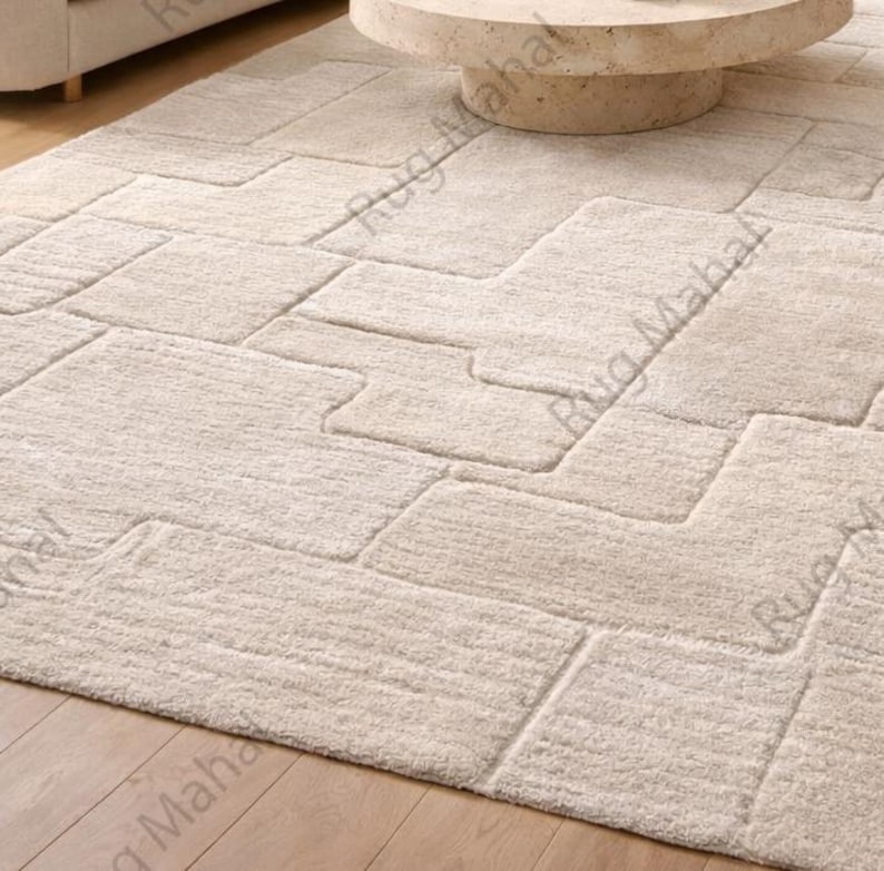 Ivory textured geometric area rug styled in a modern minimalist living room with neutral furniture.