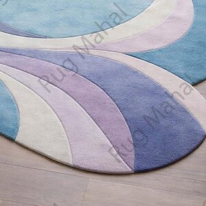 Abstract swirl shaped pastel area rug in blue, purple and white colors styled in a modern living room interior