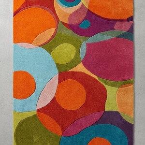 Top view of multicolor abstract rug with organic shapes and bold color blocks on a clean background.
