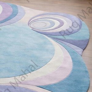 Abstract swirl shaped pastel area rug in blue, purple and white colors styled in a modern living room interior