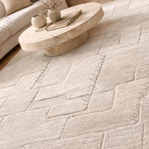 Ivory textured geometric area rug styled in a modern minimalist living room with neutral furniture.