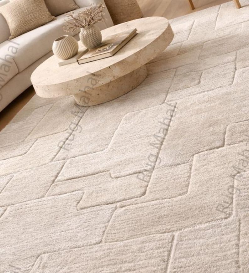 Ivory textured geometric area rug styled in a modern minimalist living room with neutral furniture.