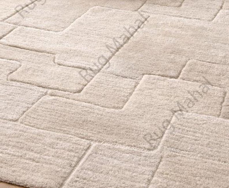 Ivory textured geometric area rug styled in a modern minimalist living room with neutral furniture.