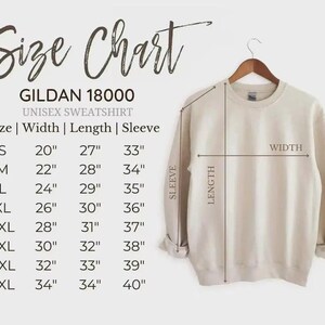 May include: A beige Gildan 18000 unisex sweatshirt hangs on a wooden hanger. The image includes a size chart with measurements in inches for width, length, and sleeve length, ranging from size small to 5XL.