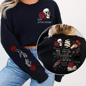 May include: Black sweatshirt with white and red graphics. The front displays a skull, roses, and the text "RUN, LITTLE MOUSE." The sleeve has a hand and skeleton hand design with roses. The back has additional graphics and text.