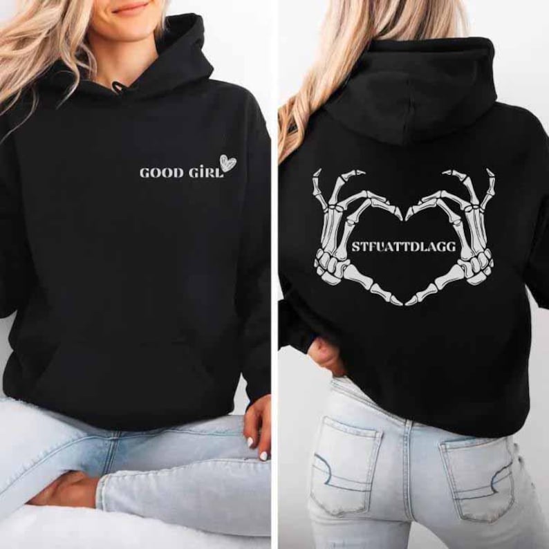 May include: Black hoodie with the text "GOOD GIRL" and a heart on the front. The back features a heart made of skeleton hands with the text "STFUATTDLAGG". The hoodie has a hood and a front pocket.